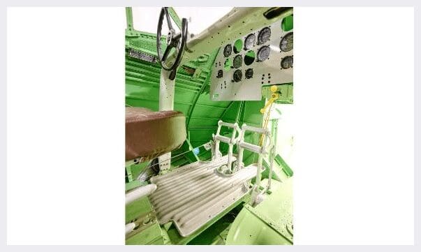 A green airplane with many controls and a steering wheel.